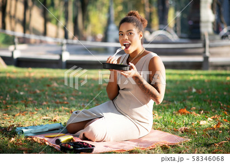 Dark-skinned woman with tattoo on arm enjoying little picnic Dark-skinned woman with tattoo on arm enjoying little picnic 58346068