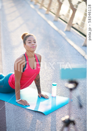 Dark-skinned woman doing yoga and filming blog Dark-skinned woman doing yoga and filming blog 58346118