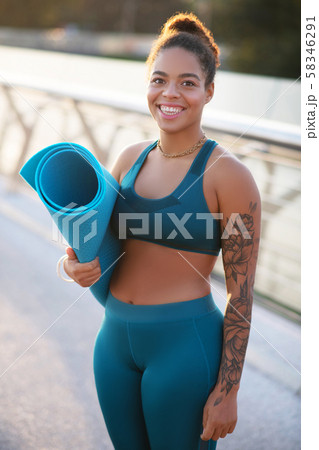 Plump smiling woman holding sport mat while heading to training Plump smiling woman holding sport mat while heading to training 58346291