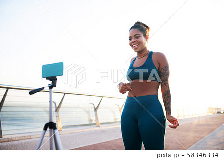 Smiling sports blogger speaking about abs while filming video Smiling sports blogger speaking about abs while filming video 58346334