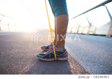Woman wearing sneakers working out with resistance band 58346461