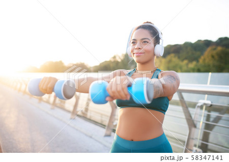 Dark-eyed woman taking dumbbells and building muscles 58347141