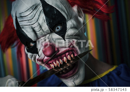 scary evil clown with a knife in his mouth 58347143