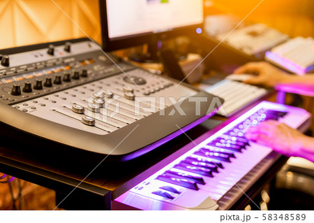 male musician composing a song in digital recording studio. shallow dept of field, focus on mixer fader 58348589