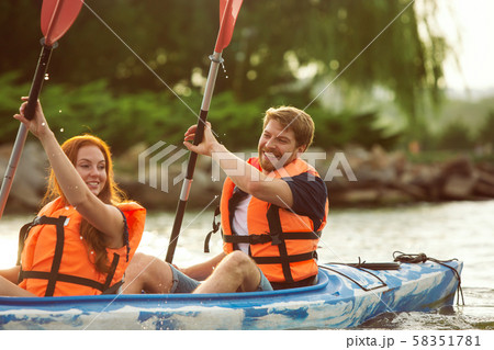 Happy couple kayaking on river with sunset on the background 58351781