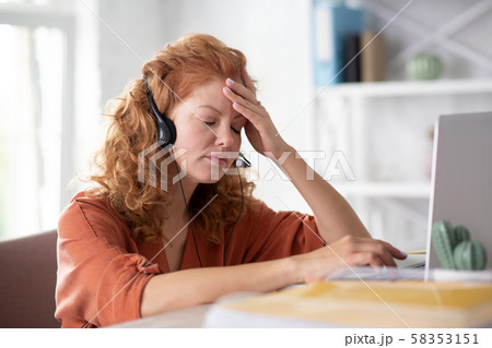 Curly woman touching her forehead while feeling dizzy 58353151
