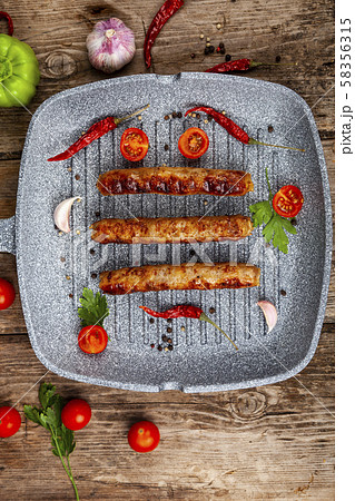 Kupaty in a frying pan, vegetables and spices. 58356315