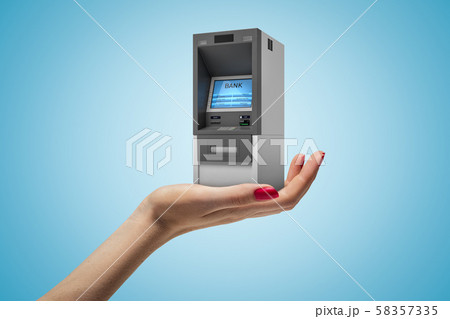 Female hand holding ATM machine on blue background 58357335