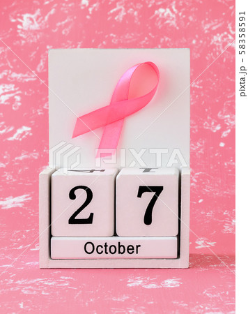 Pink ribbon of breast cancer awareness on a white wooden perpetual calendar with date 27 october. Pink ribbon of breast cancer awareness on a white wooden perpetual calendar with date 27 october. 58358591