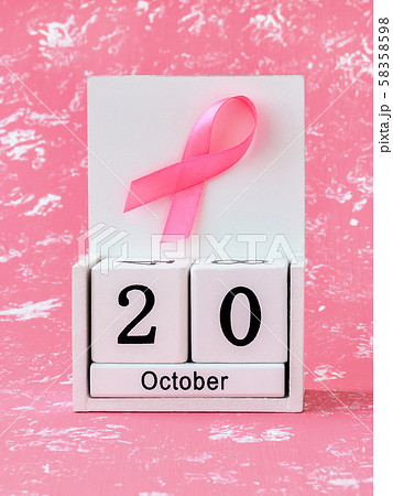 Pink ribbon of breast cancer awareness on a white wooden perpetual calendar with date 20 october. Pink ribbon of breast cancer awareness on a white wooden perpetual calendar with date 20 october. 58358598