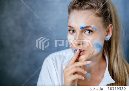 Creative fashion beauty portrait of a beautiful young blond woman with a brush for cosmetics Creative fashion beauty portrait of a beautiful young blond woman with a brush for cosmetics 58359520