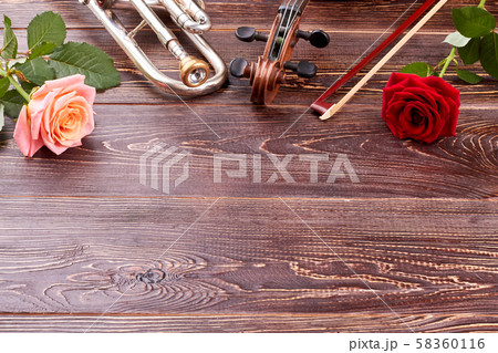 Musical instruments and roses on wooden background. 58360116