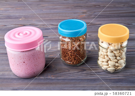 Jars of cereals on kitchen table. 58360721