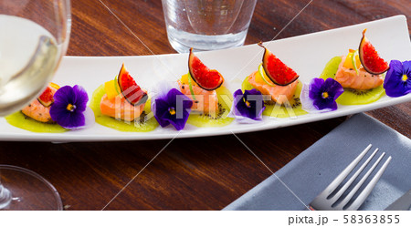 Ceviche from pickled red fish and cumquat a circle of kiwi, with figs at plate Ceviche from pickled red fish and cumquat a circle of kiwi, with figs at plate 58363855
