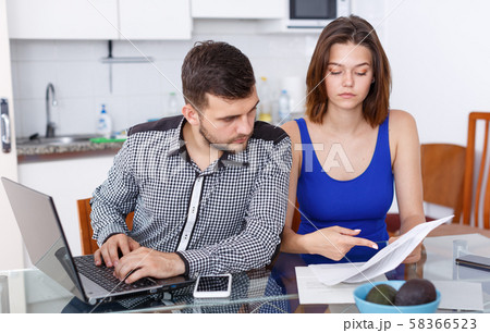 Serious young family couple with documents using laptop Serious young family couple with documents using laptop 58366523