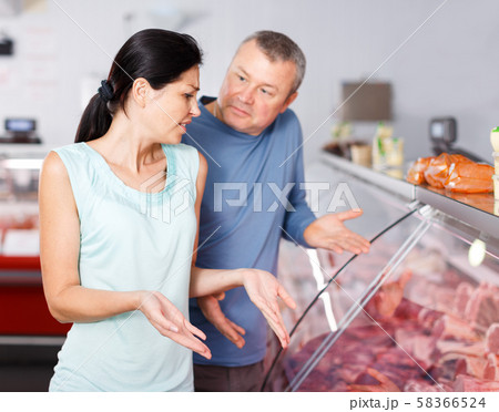 Sad couple customers choosing meat in shop Sad couple customers choosing meat in shop 58366524