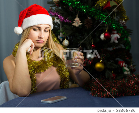 Girl is bored and drinking water in New Year night Girl is bored and drinking water in New Year night 58366736