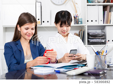 Two businesswomen working with smartphone in the office 58366892