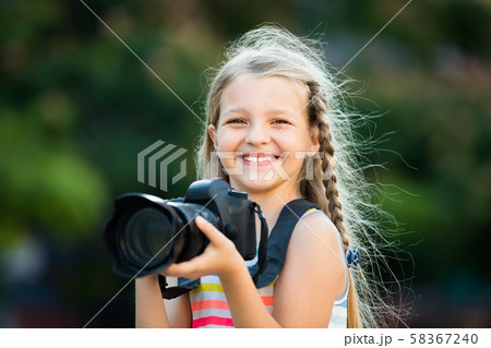 admiring female child taking pictures with camera in park 58367240