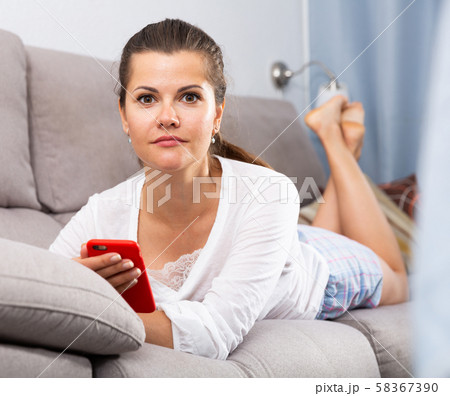 Woman lying on sofa with phone 58367390
