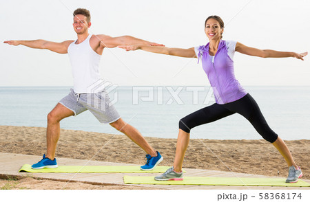 Family exercising yoga poses standing on sunny beach Family exercising yoga poses standing on sunny beach 58368174