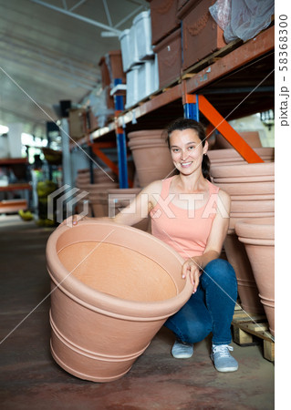 Female seller is standing near clay pots in stock 58368300
