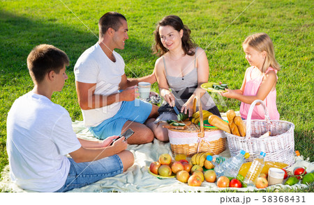 Parents with two teenagers enjoying delicious meal on the picnic Parents with two teenagers enjoying delicious meal on the picnic 58368431