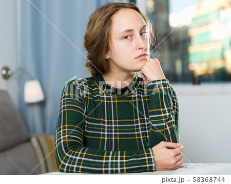 Portrait of sorrowful woman sitting at home 58368744