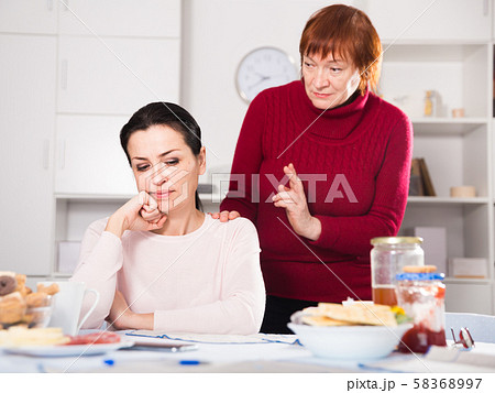Upset woman quarrel with mother at table Upset woman quarrel with mother at table 58368997