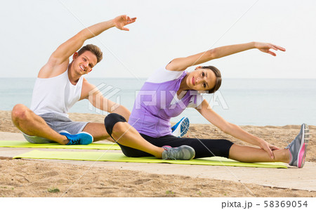 Smiling woman and guy training on beach by sea 58369054