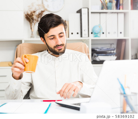 Manager with orange mug working at pc Manager with orange mug working at pc 58369102