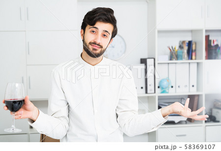 Office worker holding glass of red wine 58369107