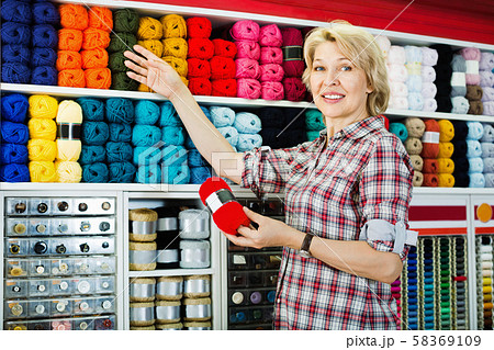 Mature glad woman customer picking various yarn Mature glad woman customer picking various yarn 58369109