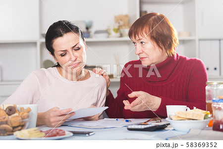 Sad young female and mother with financial documents Sad young female and mother with financial documents 58369352