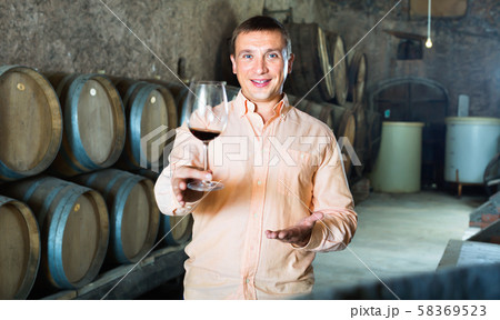 Owner of winery standing with wine in cellar 58369523