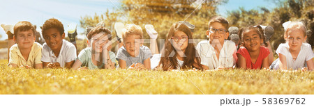 Happy children lie on the green grass on a sunny day Happy children lie on the green grass on a sunny day 58369762