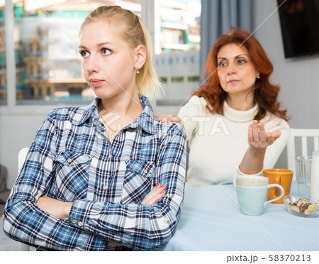 Portrait of sad mature woman trying to talk with daughter in home Portrait of sad mature woman trying to talk with daughter in home 58370213