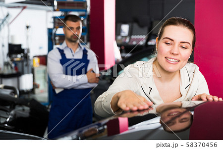 Happy woman touching surface of repainted car 58370456