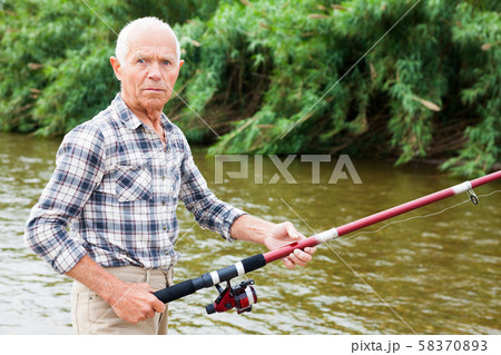 Mature man angling at riverside Mature man angling at riverside 58370893