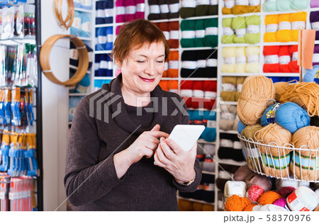 Woman with needlework accessories and talking on phone 58370976