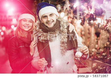 Girl with boy in Christmas hat choosing decorations Girl with boy in Christmas hat choosing decorations 58371067