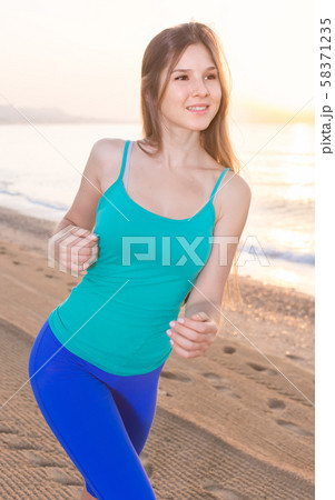 Smiling adult woman in blue T-shirt is jogging 58371235