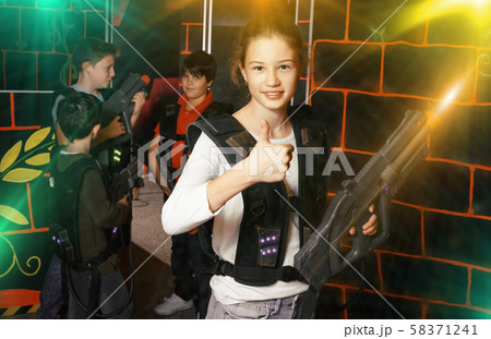 Cheerful teen girl standing with laser pistol in dark lasertag r Cheerful teen girl standing with laser pistol in dark lasertag r 58371241