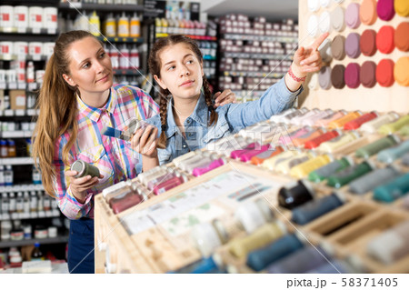 Mother and daughter holding jar with color paint 58371405