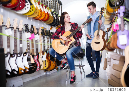 Teenagers examining guitars in shop Teenagers examining guitars in shop 58371606