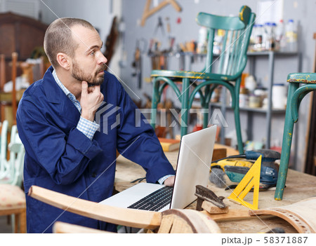 Carpenter using laptop in workshop Carpenter using laptop in workshop 58371887