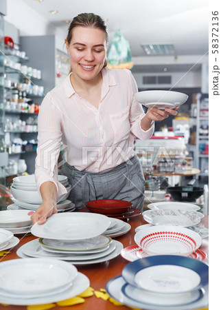 Young woman customer choosing dishes in the tableware store 58372136