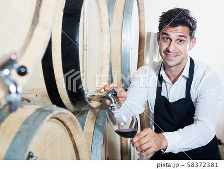 Seller pouring wine in cellar Seller pouring wine in cellar 58372381