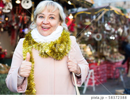 Positive female in tinsel on Christmas fair 58372388