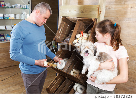 girl with father choosing dog treats 58372828